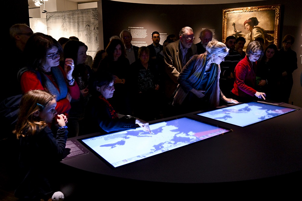 People in exhibition looking at interactive maps