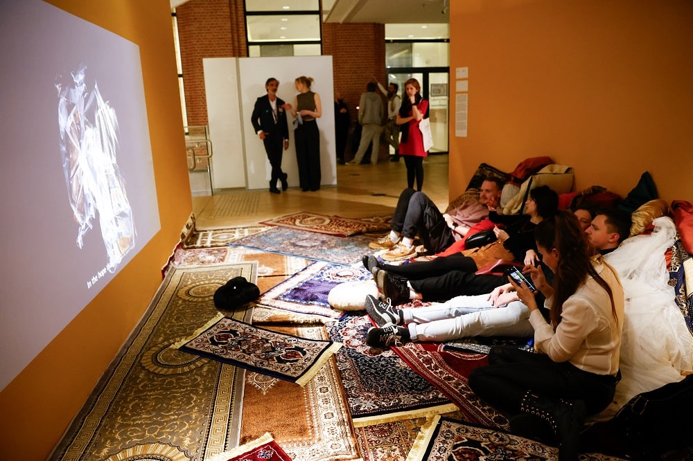 People in exhibition sitting on carpets