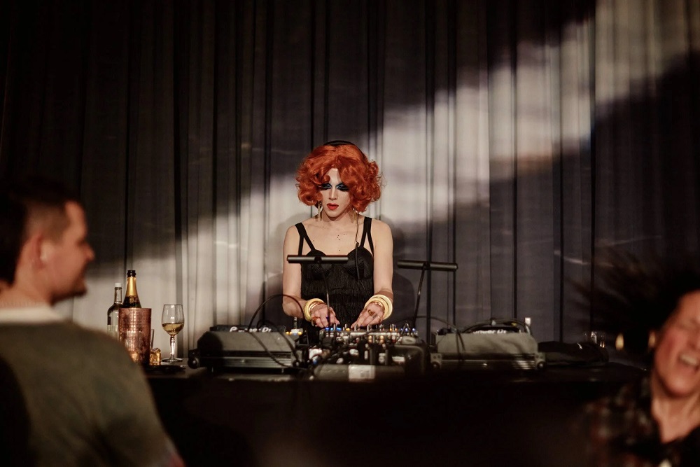 DJ mit roten Haaren auf Decks