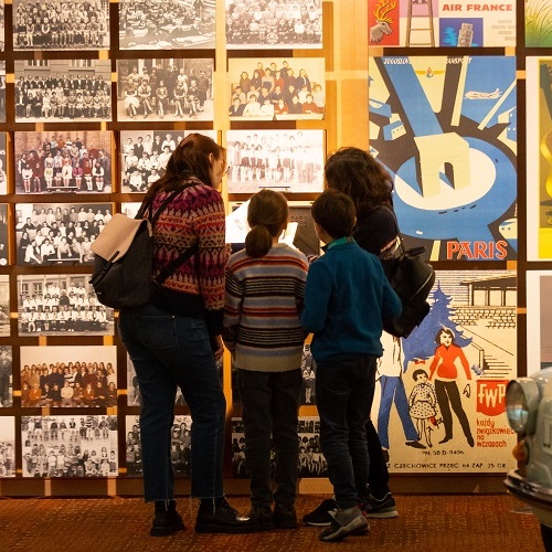 Une famille regarde des photos de classe dans un musée.