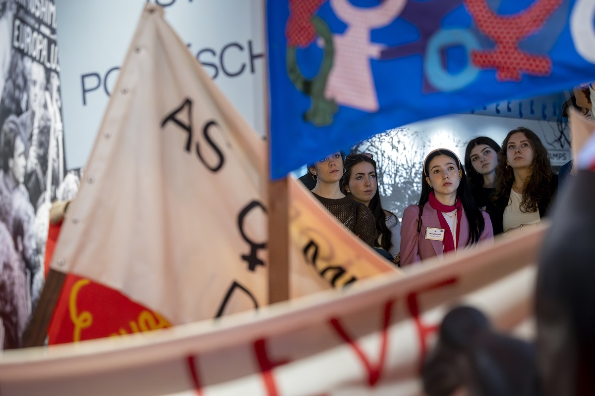 Women on guided tour in front of feminist flags