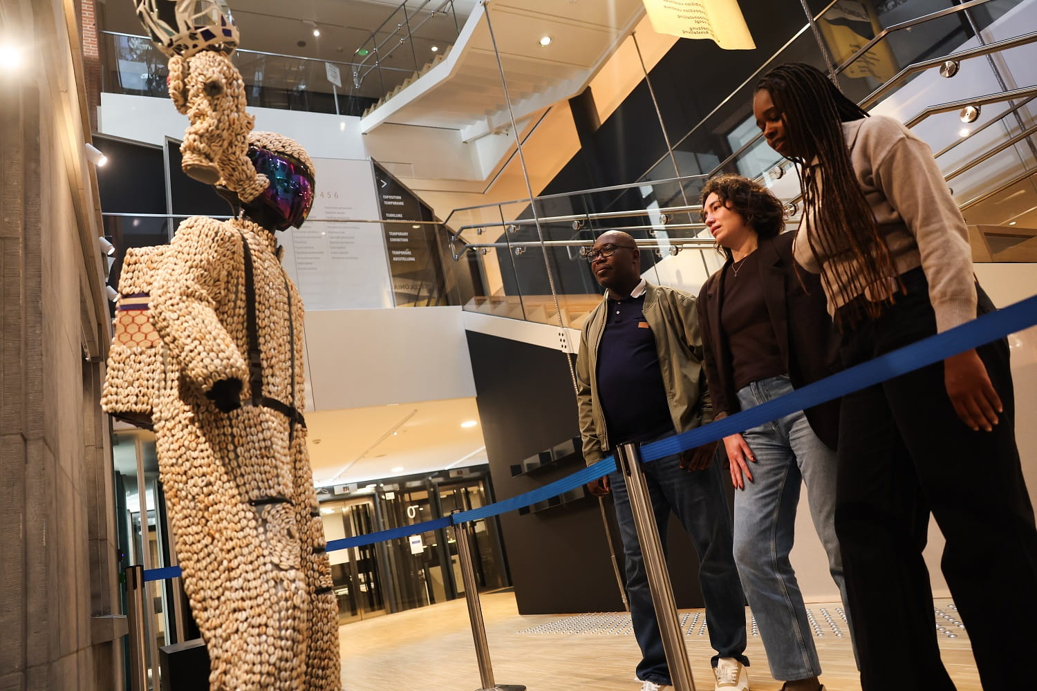 Three people looking at art model of astronaut