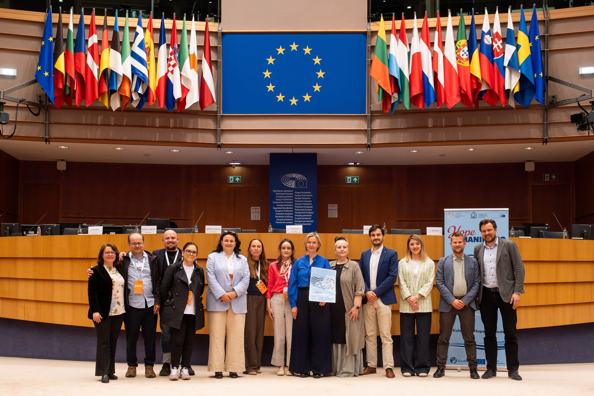 Group in hemicycle in front of European flags