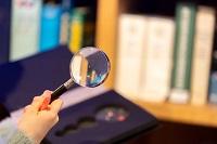 Child with magnifying glass on book