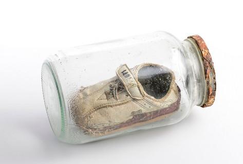 Baby&#039;s shoe protected in glass bottle by refugee