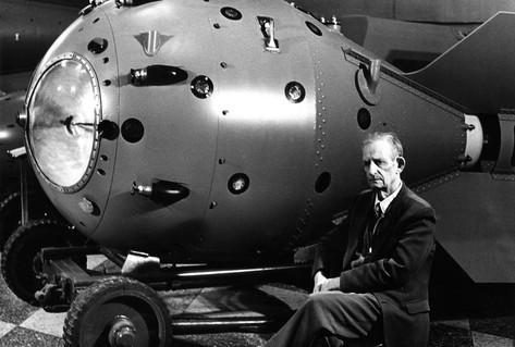 Black white photograph man sitting beside atomic bomb