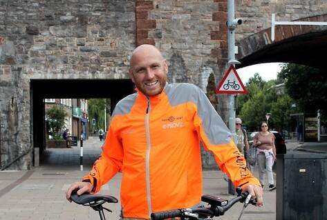 Man in front of bicycle in orange jacket