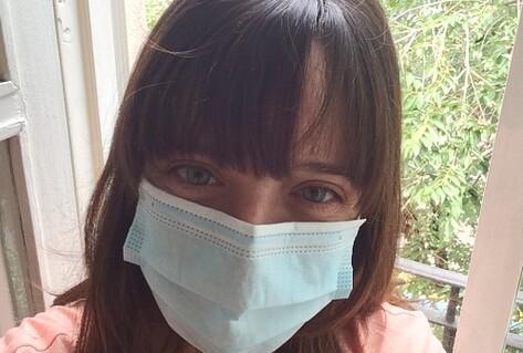 Young woman on balcony wearing mask