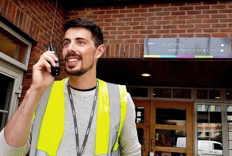 Man in yellow waistcoat on walkie-talkie
