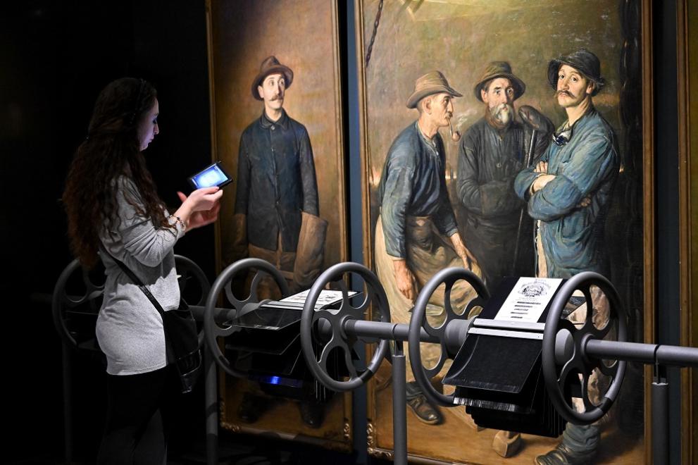 Visitor using tablet in front of worker painting