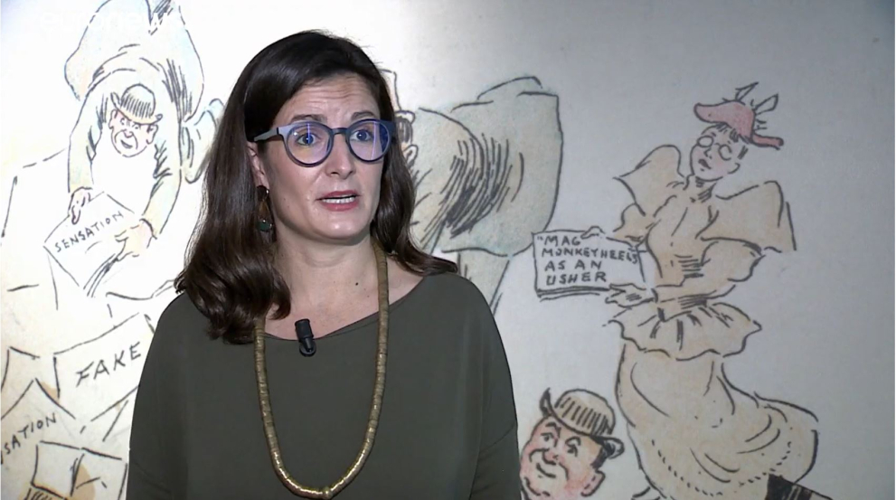 Curator giving interview in front of fake news display