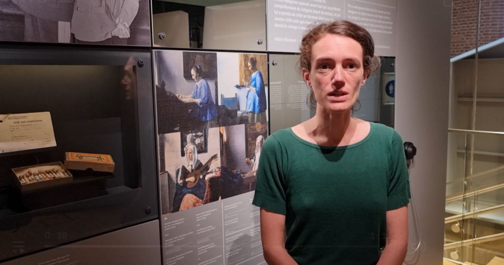 Curator giving interview in front of display