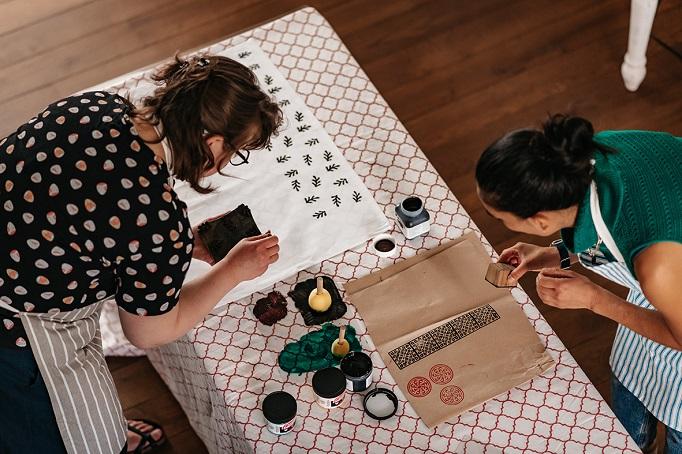 Two women creating printing materials on table